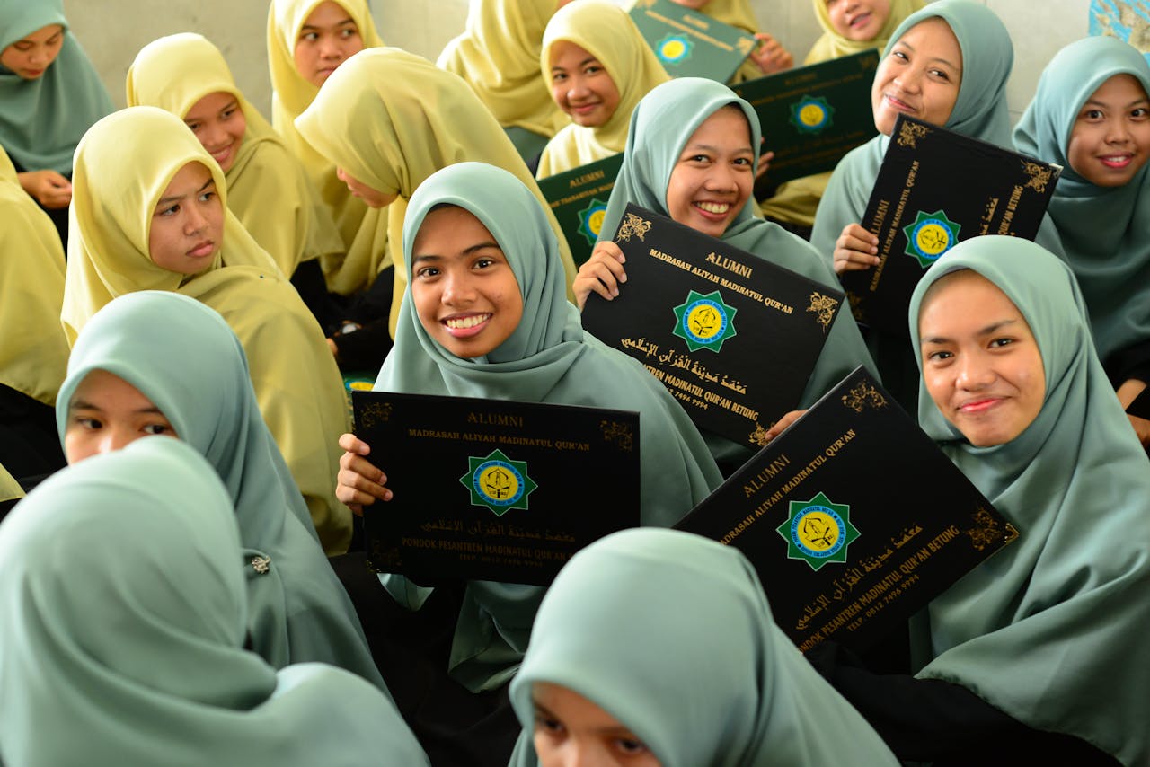 why-choose-us Group of young Muslim students celebrating graduation, holding diplomas with smiles.