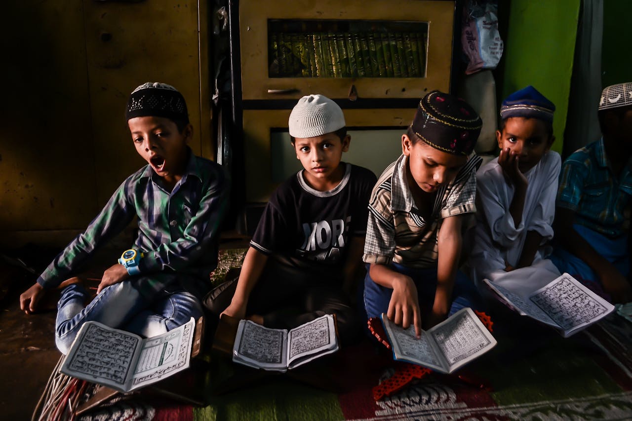 gallery-6 Group of boys engaged in religious study indoors, focused and attentive.