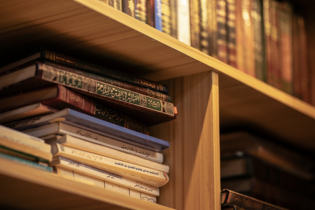 services-02 A stack of Islamic religious books on a wooden shelf, highlighting Arabic scripts and cultural significance.