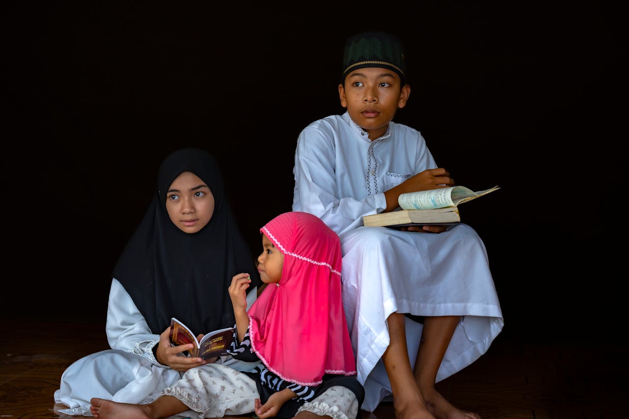 Mastering the First Impression: Your intriguing post title goes here A group of three children in traditional attire reading religious texts with focus and concentration.